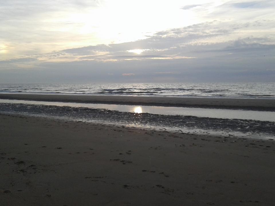 strand De Panne en ondergaande zon bij zee La Tourelle De Panne